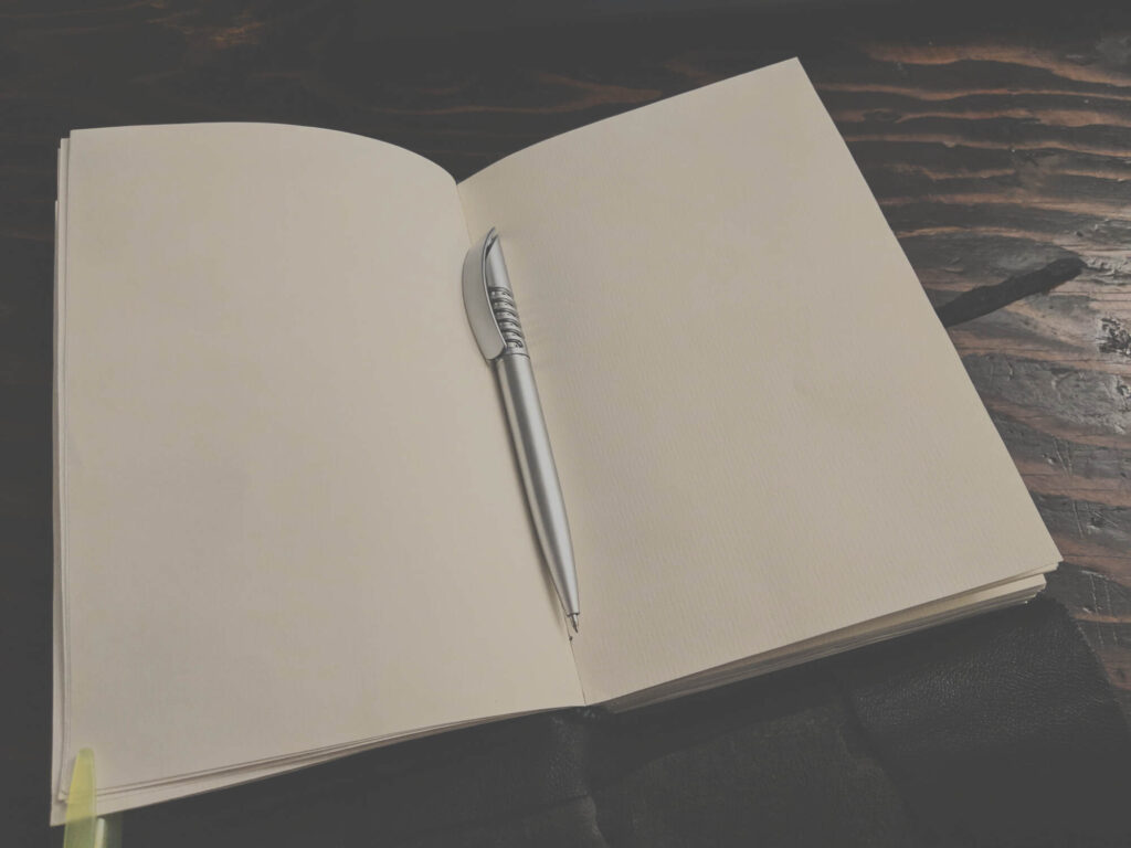 An open blank notebook with a pen along the crease